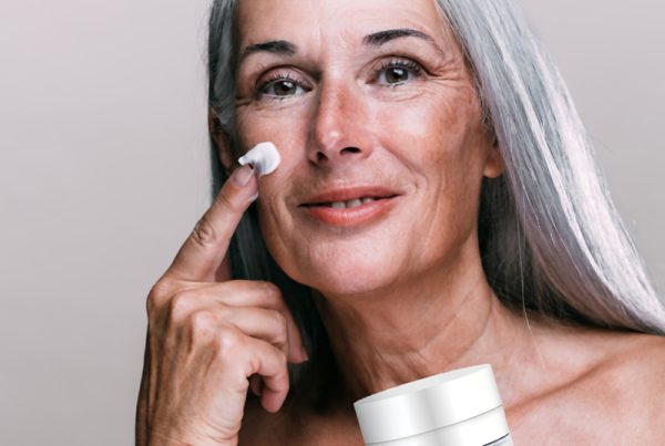 Mature woman with good skin holding moisturiser