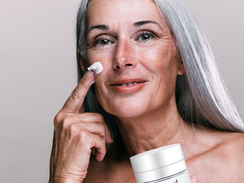 Mature woman with good skin holding moisturiser