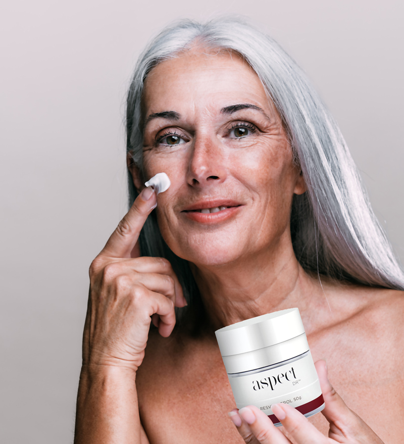 Mature woman with good skin holding moisturiser